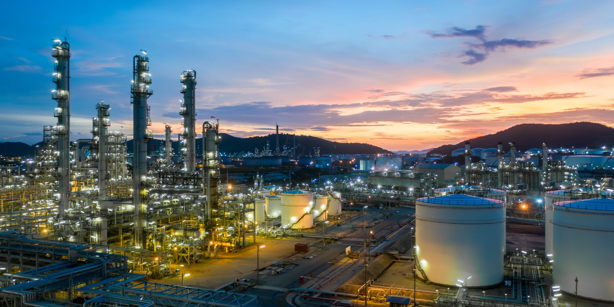 Process plant with distillation columns and storage tanks at dusk